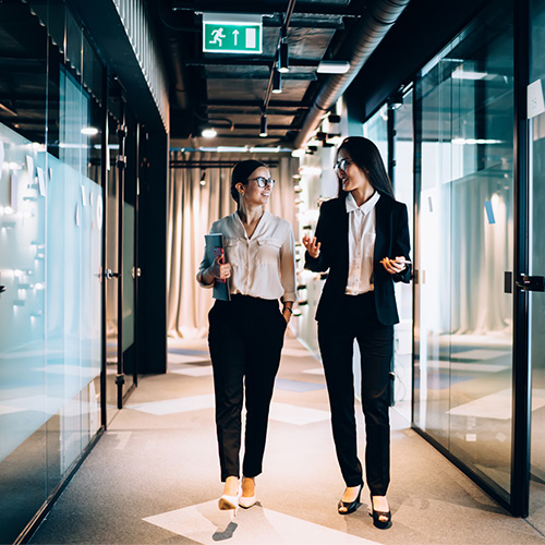 Two Women Walking Through Halls at Work